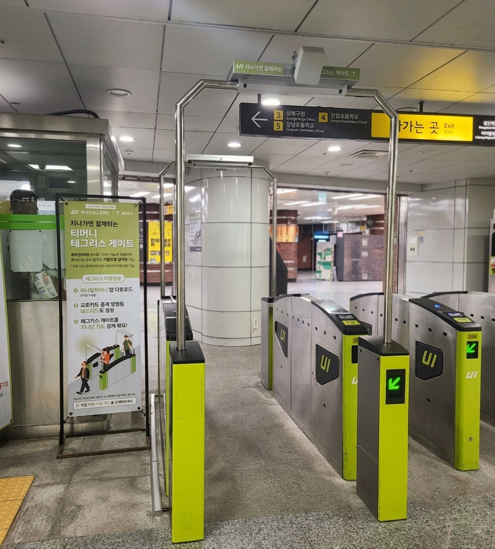 Green Tmoney Tagless gates beside an explanatory sign in a Seoul subway station